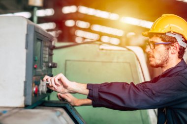 Genç profesyonel teknisyen makineyi ağır sanayi fabrikasındaki otomatik Cnc 'ye çalıştırıyor..