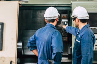 Makine bakım mühendisi ekibi fabrikanın arka görünümünde takım çalışması yapıyor..