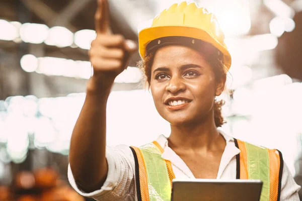 工場メンテナンスエンジニアのアメリカ人女性労働者は 労働者の福祉の概念の将来のための安全制服とヘルメットの手を指して笑顔を身に着けて働く幸せ — ストック写真