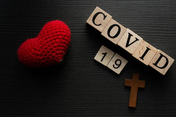 COVID-19 name of Corona virus from Wuhan text word on drak wood background with heart love.
