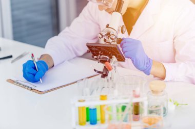 Laboratuvarda çalışan, not alan veya tıp fakültesi laboratuarında araştırma kağıtları yazan yakın bir bilim adamı.