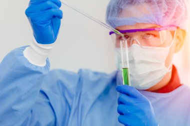 Tehlike virüsü tıbbi test araştırması yapan bilim adamı Doktor. Antibiyotik tıp, biyolojik tehlike önleyici mavi üniforma giyiyor.