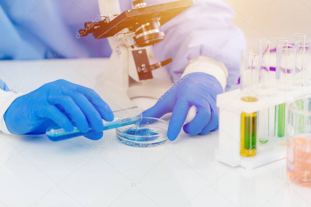 Scientist medical lab technician mixing chemical solution for reaction observing by microscope