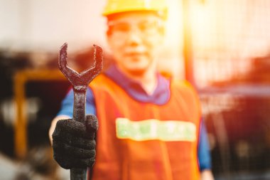 Tamirci ya da tamirci endüstriyel ingiliz anahtarı mühendisi güvenlik giysisi ve miğferiyle endüstri fabrikasında çalışıyor..