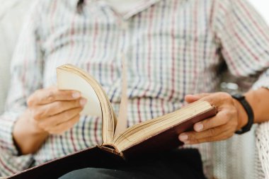 Yakından yaşlı bir adam kitap okuyor.