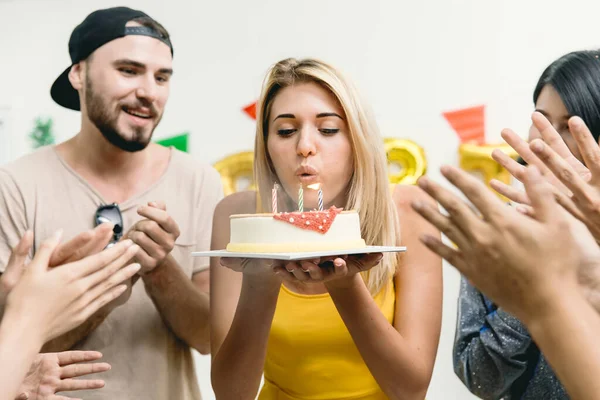 美丽的女孩在聚会上和朋友们一起吹响生日蛋糕 拍拍她的生日歌 — 图库照片