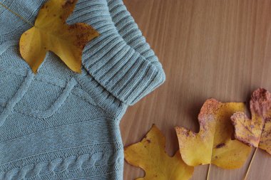  Sıcak örgü süveter ve sarı yapraklar masanın üzerinde..
