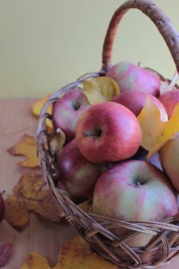 Kırmızı elma ve sarı yapraklar sepette.
