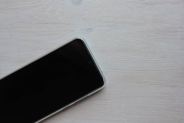 Akıllı telefon, açık ahşap bir arka planda yatıyor..