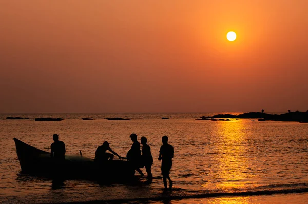 Fishermen going to fishing on a boat in the sea at sunset, Goa, India.