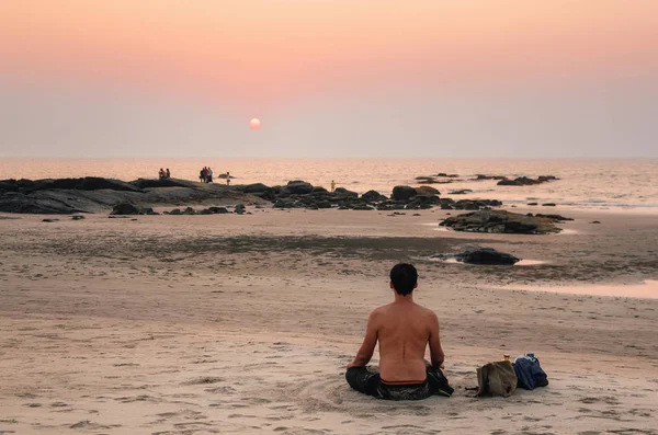 Homem sentar-se posição de lótus na praia do mar ao pôr do sol — Fotografia de Stock