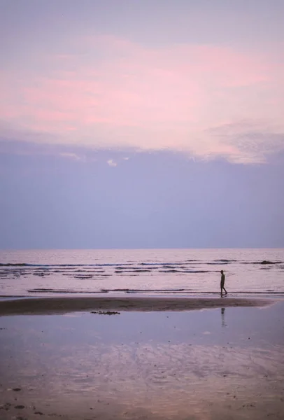 Homem caminhando ao longo da costa da praia ao pôr do sol — Fotografia de Stock