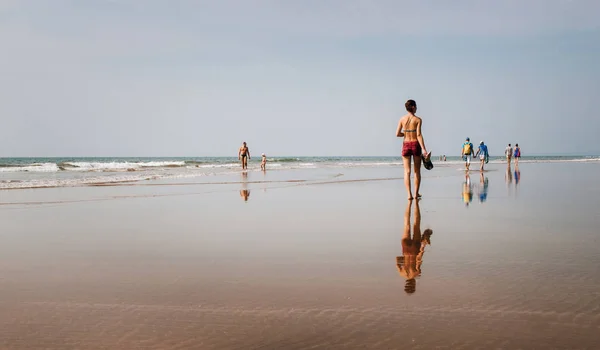 As pessoas caminham na praia com reflexos espelhados, Goa, Índia — Fotografia de Stock