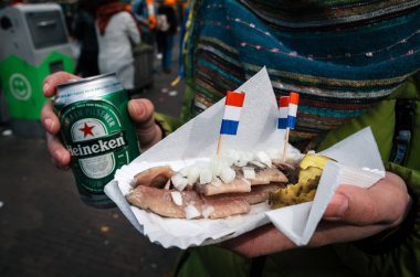 Eller bir Heineken bira ve ringa balığı turşusu ve soğan ile Hollandalı bir incelik.