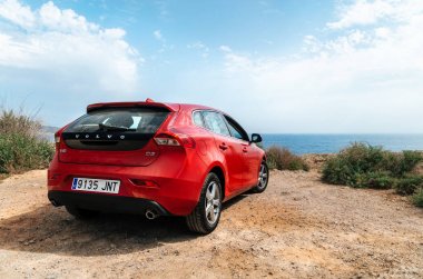 Kırmızı araba Volvo v40 cliff karşı deniz kenarında duran.
