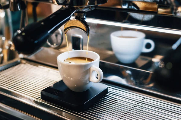 Espressomachine koffie gieten in witte kop Stockafbeelding