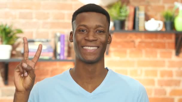 Портрет чернокожего юноши демонстрирует знак победы — стоковое видео