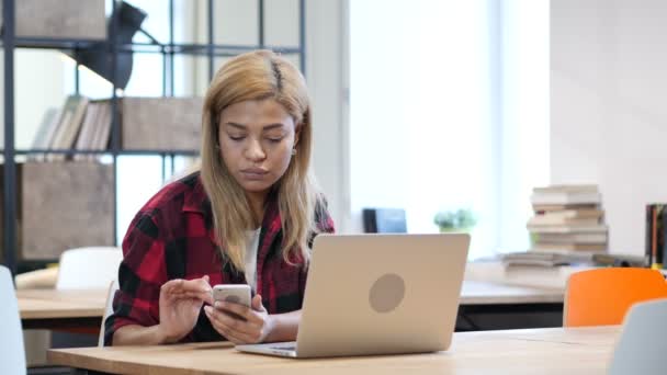 Donna nera utilizzando smartphone, seduto in ufficio — Video Stock