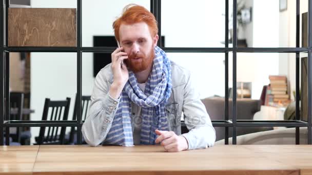 Человек разговаривает по смартфону, сидит в офисе — стоковое видео