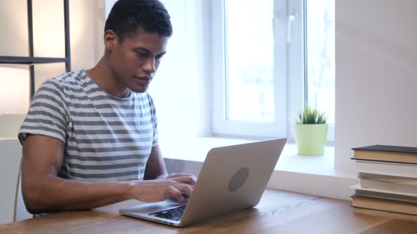 Czarny człowiek świętuje sukces podczas pracy na laptopie — Wideo stockowe