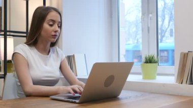 Ofiste dizüstü bilgisayar üzerinde çalışan dalgın genç kız