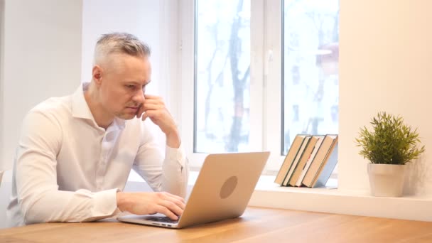 Pensivo homem de meia-idade trabalhando no laptop no escritório — Vídeo de Stock