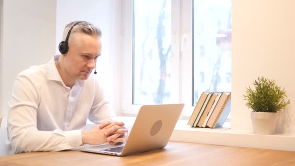 Usmívající se muž středního věku při práci se sluchátky — Stock video