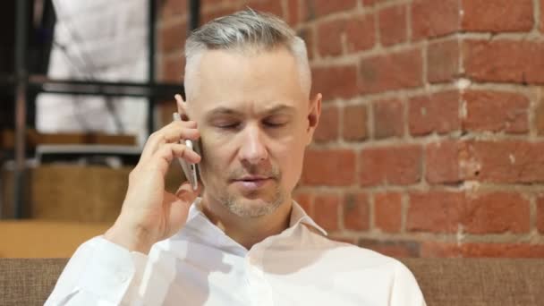 Conversación telefónica, hombre de mediana edad respondiendo a una llamada en el trabajo — Vídeos de Stock
