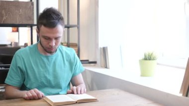 Genç adam kitap okuyor.