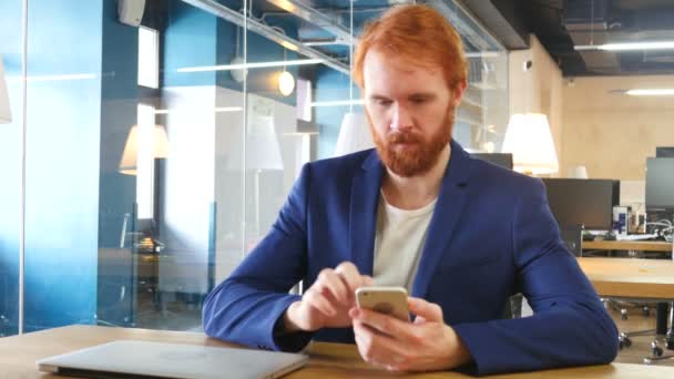 Homem usando Smartphone no trabalho, cabelos vermelhos — Vídeo de Stock