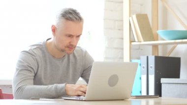 Ofiste dizüstü bilgisayarda çalışan adam kızgın orta yaşlı