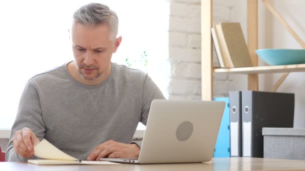 Middle Aged Man lezing op het werk in zijn kantoor — Stockvideo