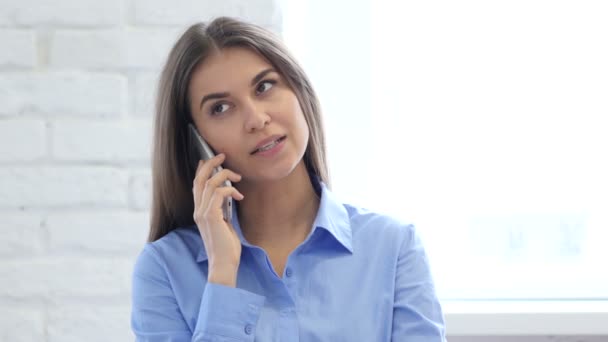 Женщина на работе разговаривает по смартфону с клиентом — стоковое видео