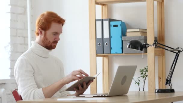 Homem de cabelos vermelhos lendo no trabalho em seu escritório — Vídeo de Stock