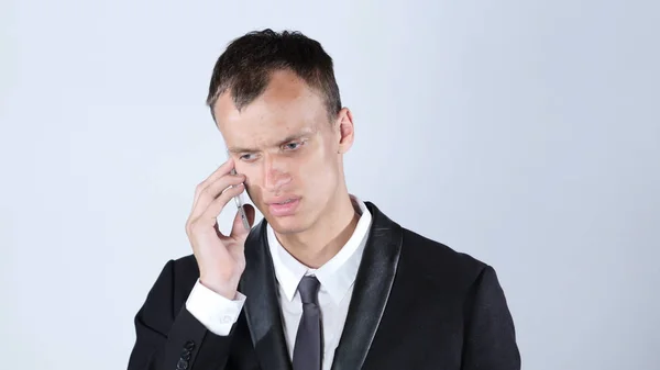 Jovem empresário perturbado falando no smartphone — Fotografia de Stock