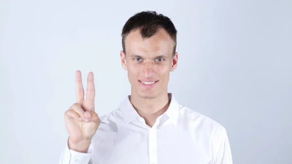 Portrait of young man smiling and showing you victory sign on white background — Stock Photo, Image