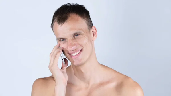 Молодой человек без рубашки разговаривает по мобильному телефону — стоковое фото