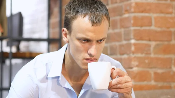 Jovem atraente homem beber um café no espaço de trabalho criativo — Fotografia de Stock