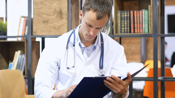 Medical office - male doctor looking down reading documents thinking