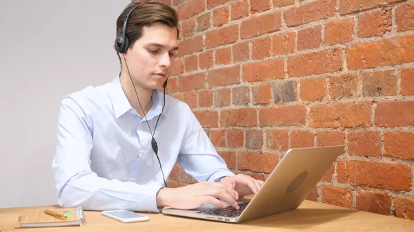 Homem usando fone de ouvido para falar, trabalhando Online — Fotografia de Stock