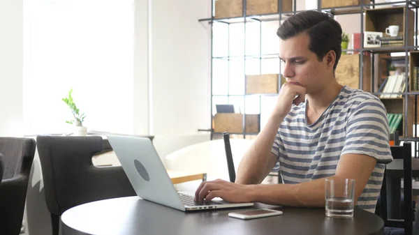 Junger Mann mit Laptop, der arbeitet und denkt — Stockfoto