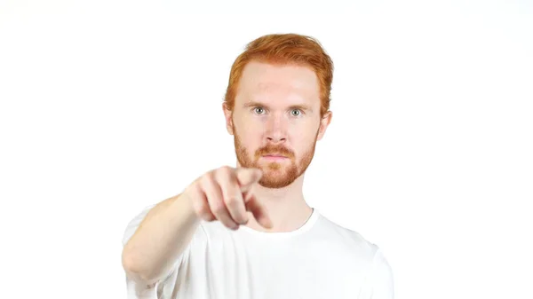 Mosolygós vörös hajú fiatalember, ujjal mutatva a fényképezőgép, fehér háttér — Stock Fotó