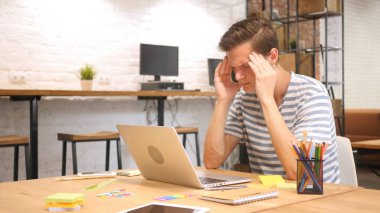 Dizüstü bilgisayarda, baş ağrısı çalışan sinirli yaratıcı tasarımcı