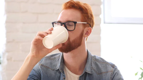 Hombre tomando un sorbo de café, sentado en la oficina — Foto de Stock