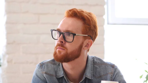 Pensando en un hombre pensativo con barba y cabellos rojos —  Fotos de Stock