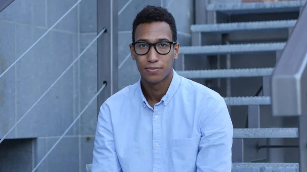 Lächelnder junger schwarzer Mann sitzt auf der Treppe, Porträt im Freien — Stockfoto