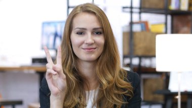 Kız ofis çalışanı, iş yerinde zafer işareti