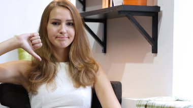 Başparmak aşağı, koltukta oturan mutsuz sevimli güzel kız