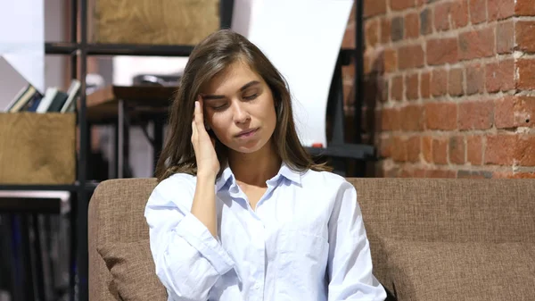 Головний біль, дівчина сидить на дивані в офісі лофт — стокове фото