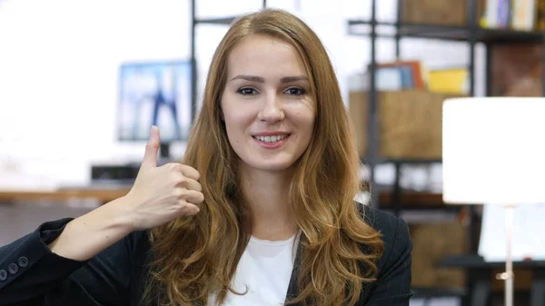 Daumen hoch von jungen Mädchen bei der Arbeit, die zufrieden im Büro sitzen — Stockfoto